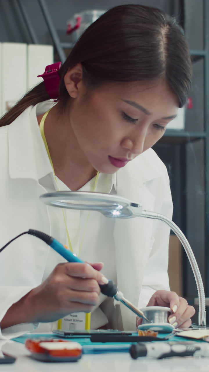Female Technician Repairing Phone with Soldering Iron