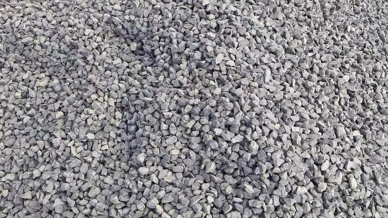 A Close Up Shot Of Black And Grey Crushed Stone Kapchi (Aggregate Crusher Stone dust ) At  A Construction Site. Camere Moving right To Left