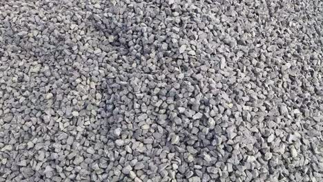 a close up shot of black and grey crushed stone kapchi (aggregate crusher stone dust ) at  a construction site. camere moving right to left