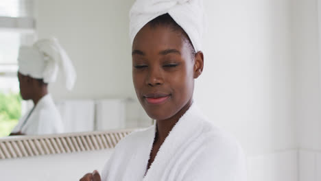 portrait of african american woman in bathrobe smiling in the bathroom at home