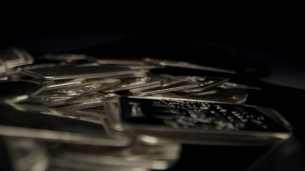 Beautiful macro dolly of shiny silver bars lying on velvet fabric in a dark room