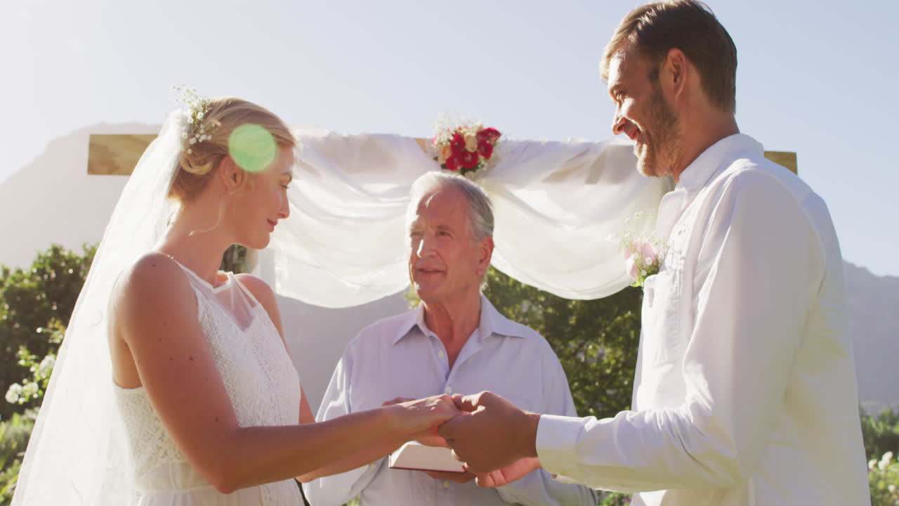 백인 신부 와 신랑 이 의식 중 결혼식 의 담당자 와 함께 야외 제단 에 서 있다