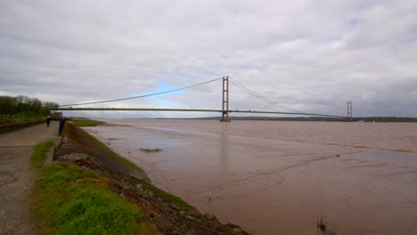 extra wide shot of the humber bridge showing exposed mud flats on the humber estuary with footpath