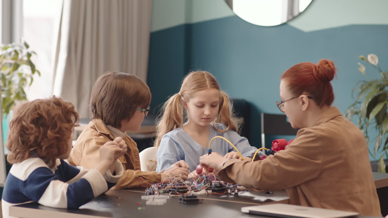 Young Female Tutor and Three School Kids Constructing Robots
