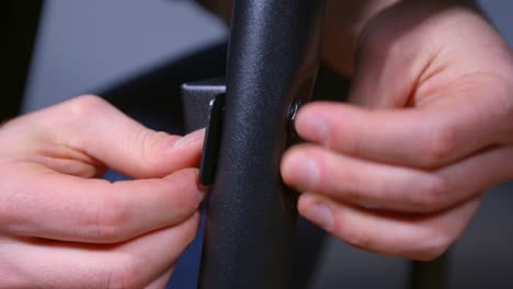 A-close-up-shot-of-a-mans-sturdy-hands-working-on-a-DIY-assembly-metal-stand,-securing-the-legs-to-a-brace-by-inserting-a-bolt-and-tightening-it-with-a-nut