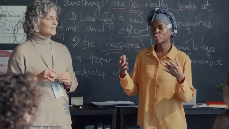 Studentessa di colore che recita una lezione di inglese davanti ai compagni di classe e all'insegnante.