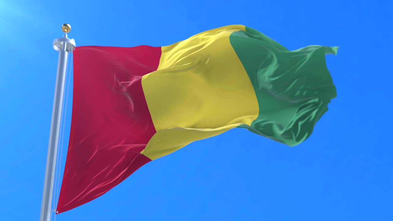 Flag of Guinea waving at wind in slow in blue sky, loop