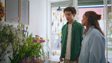 joyful lovers shop flowers in florist store. multiracial couple enjoy bouquet.