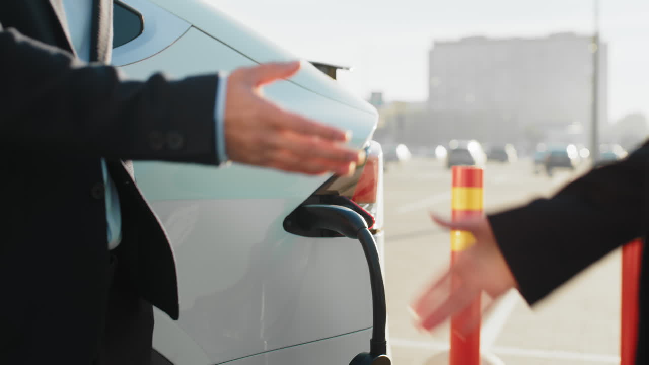 전기 차량 충전소 에서 손을 흔드는 사업가 들