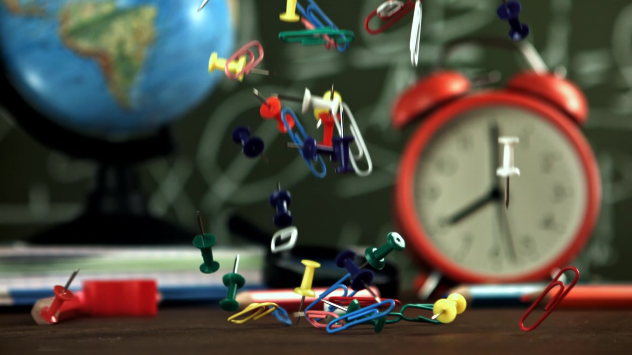 Slow Motion of Colorful Thumbtacks and Paper Clips Falling on a School Desk
