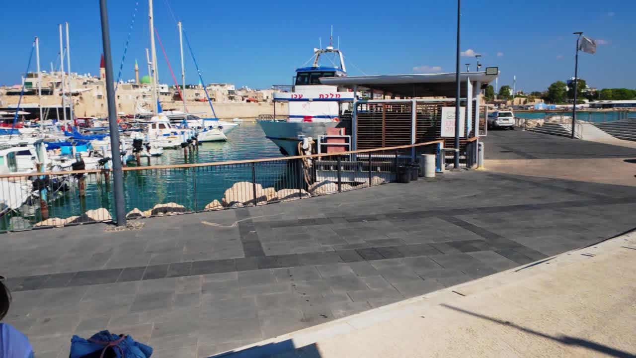 Young woman sitting on the pier watching fishing boats docked in the old city port of Akko Israel
