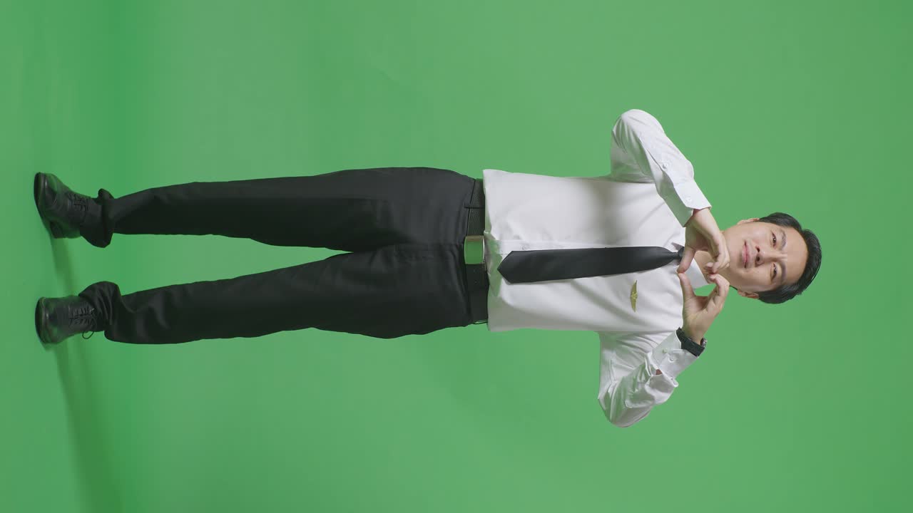 녹색 화면 배경에 심장 몸짓을 하고 미소 짓는 아시아 남성 조종사의 몸이 가득 차 있습니다.