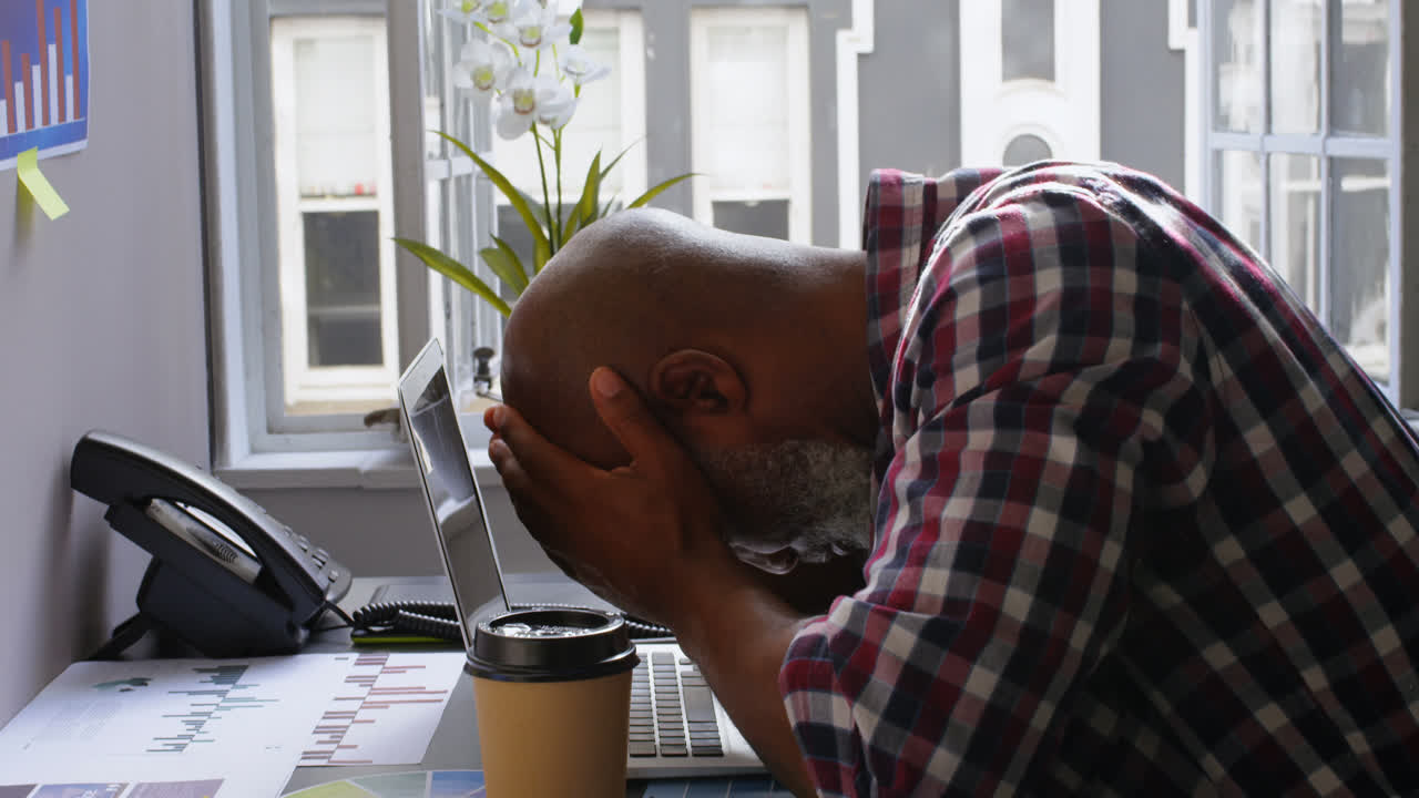 Stressed businessman sitting on desk with hand on forehead 4k