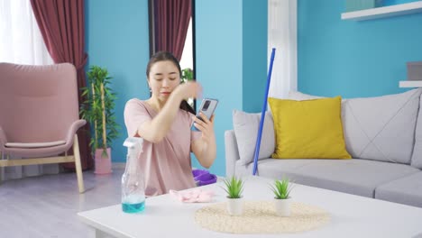 cheerful asian young woman cleaning and talking facetime.