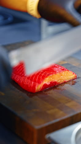 male hands wearing black latex gloves cut the piece of salmon. cooking fresh fish dishes. close up. vertical video.