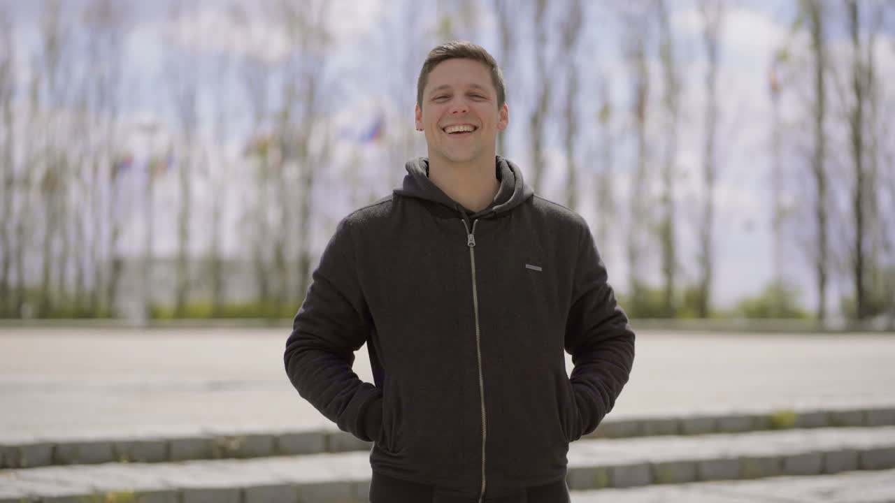 예쁜 행복한 젊은 남자가 야외에서 카메라에 미소 짓고 있습니다.