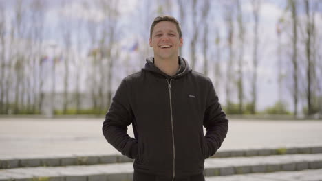 Handsome-happy-young-man-smiling-at-camera-outdoor