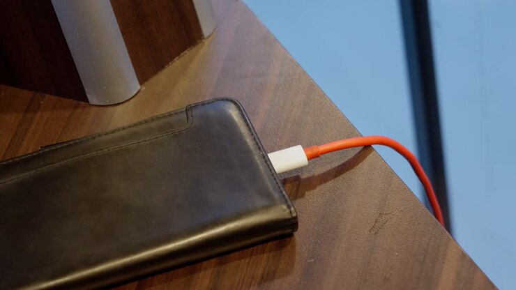 Red usb charging cable removed from cellular phone after charging, close up