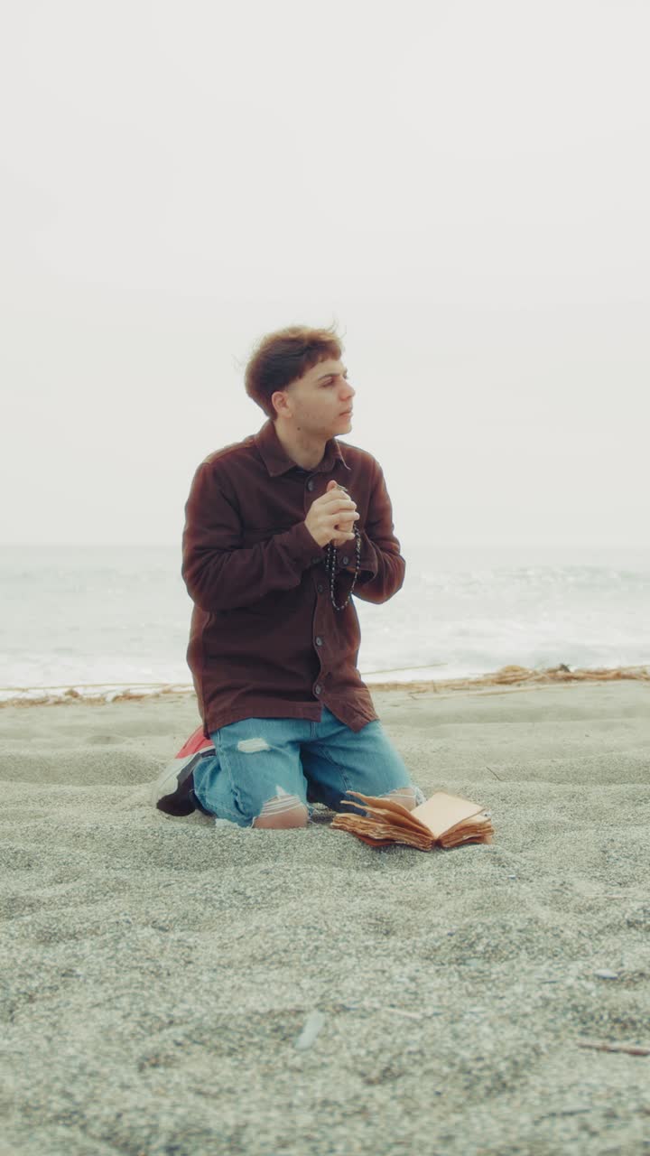 Faithful Man Praying God At The Sea On His Knees During Overcast Day