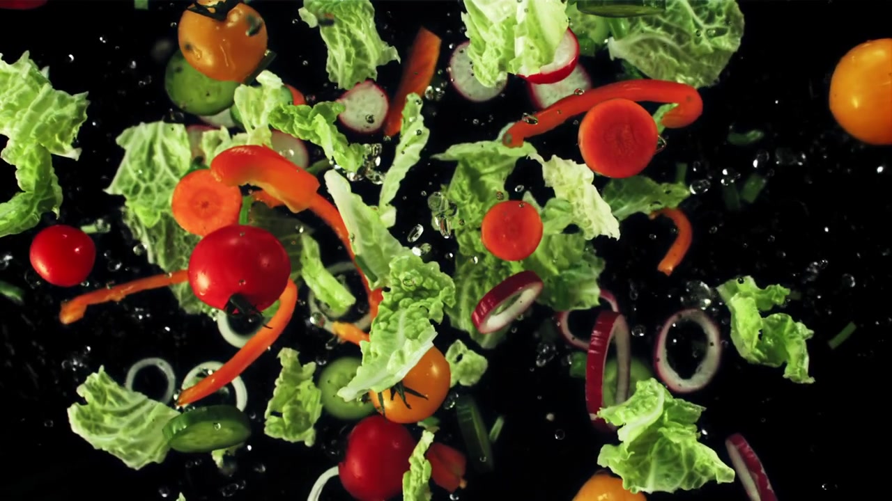 Verdure fresche per insalata che cadono e si mescolano al rallentatore.