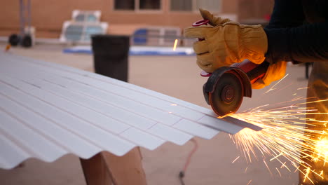 a construction worker using a power tool angle grinder to cut metal and send glowing bright sparks flying in slow motion