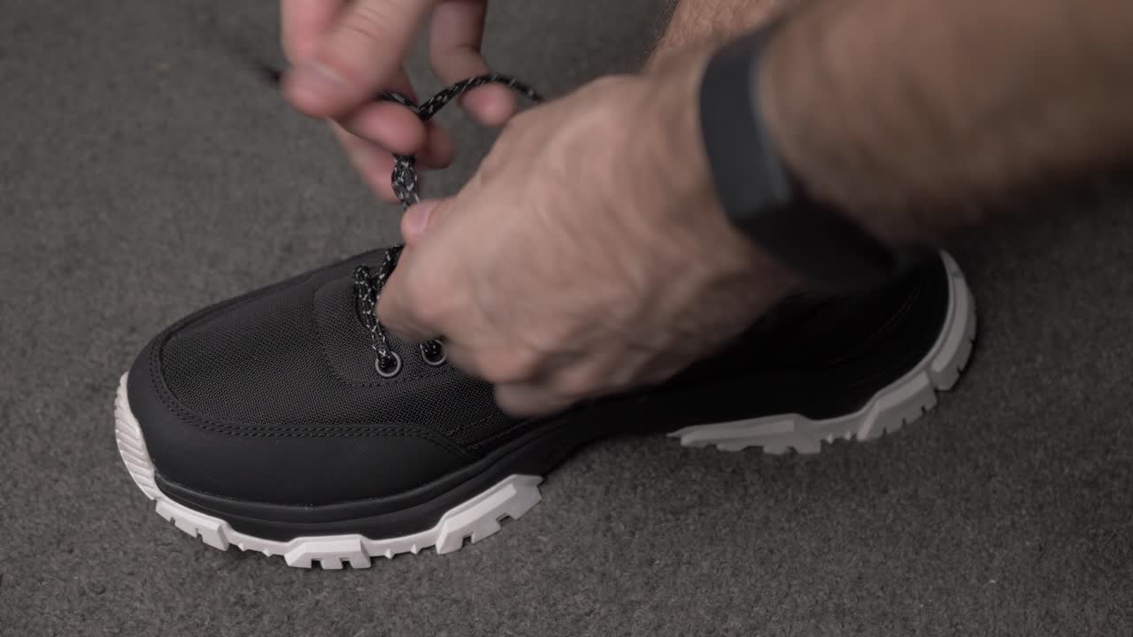 그의 검은 운동화 신발을 묶는 남성