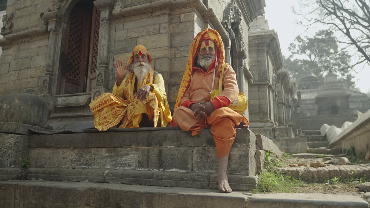 A Sadhu Yogi in yellow attire meditates with sacred hand mudras at Pashupatinath Temple, Kathmandu, Nepal. His devotion to the gods symbolizes Hindu spirituality, culture, and sacred tradition