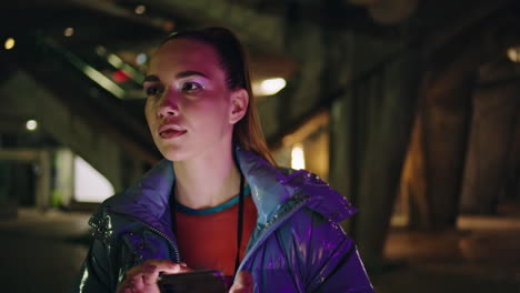 la cara de la mujer iluminada por el teléfono en la noche de la ciudad de cerca. niña usando el teléfono al aire libre