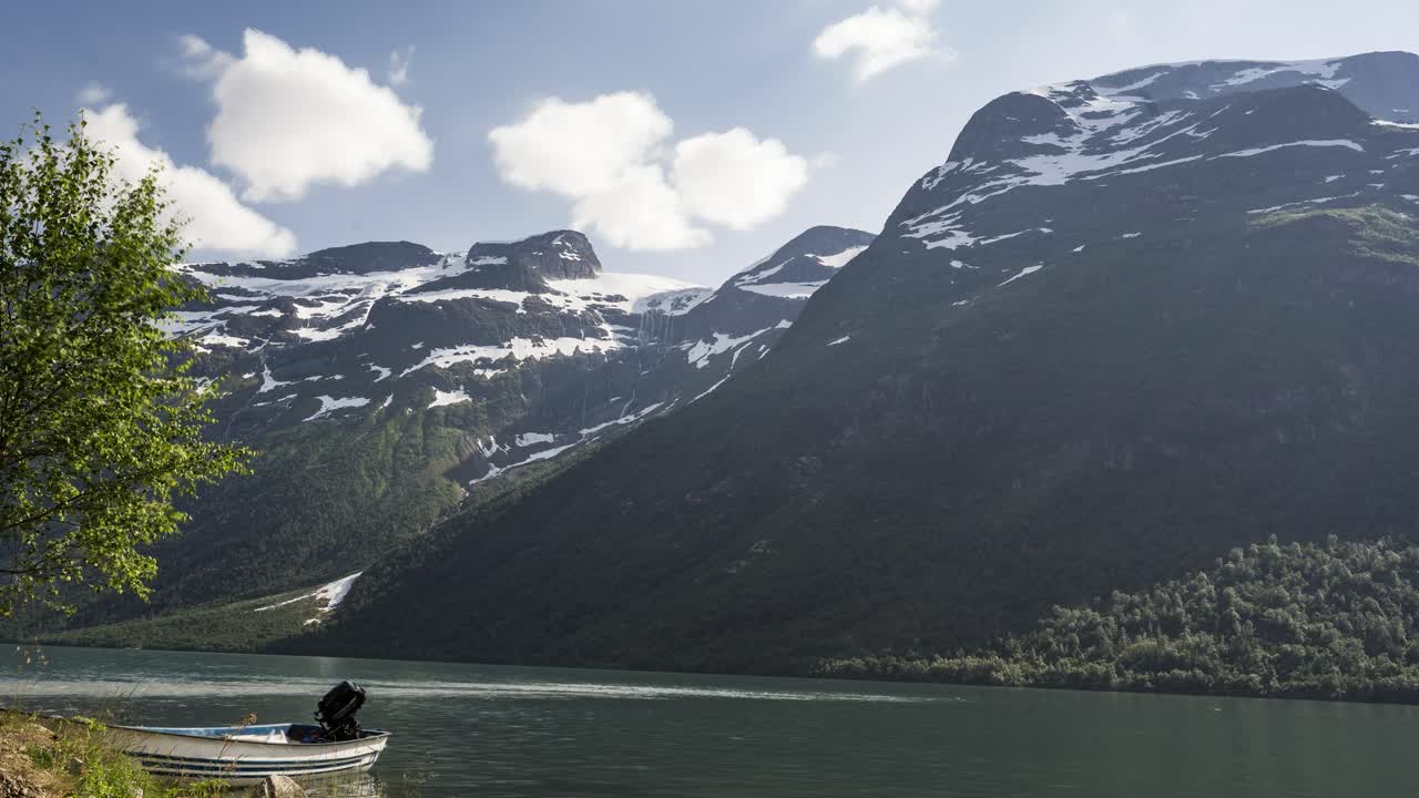 barco amarrado en la orilla del lago en el fiordo durante el invierno con montaña rocosa en el fondo - lapso de tiempo de movimiento