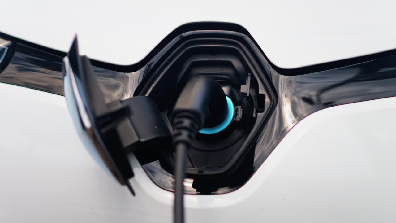 Close up of an electric car charger plugged into a white car