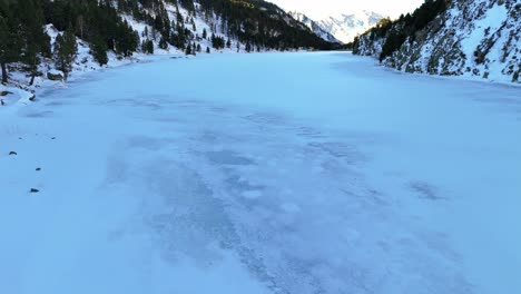 drone footage over a frozen lake in the pyrenees mountains