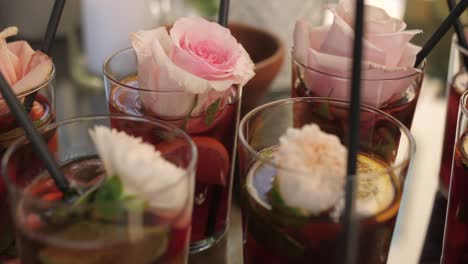 cocktail with rose decoration in glass, closeup dolly of fancy drink at party