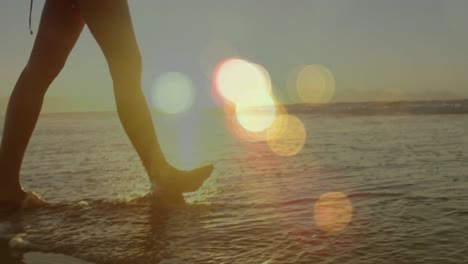 animation of light spots over caucasian woman walking on beach