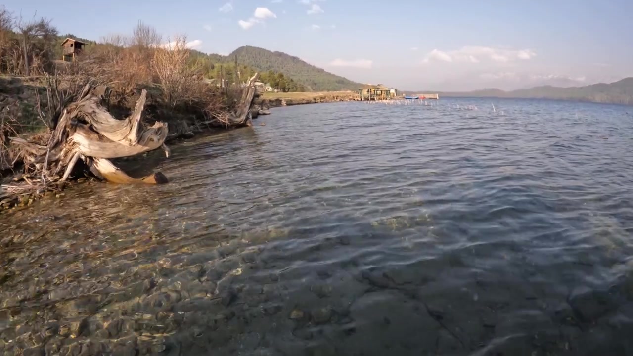 Rara Gölü'nün berrak suları, çevredeki dağları ve ormanları yansıtarak Nepal Himalayaları'nın doğal güzelliğini sergiliyor.