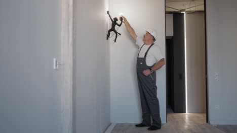 an electrician screws a light bulb into a monkey lamp.