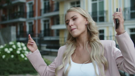 Portrait-excited-businesswoman-dancing-with-phone-in-hand-outside