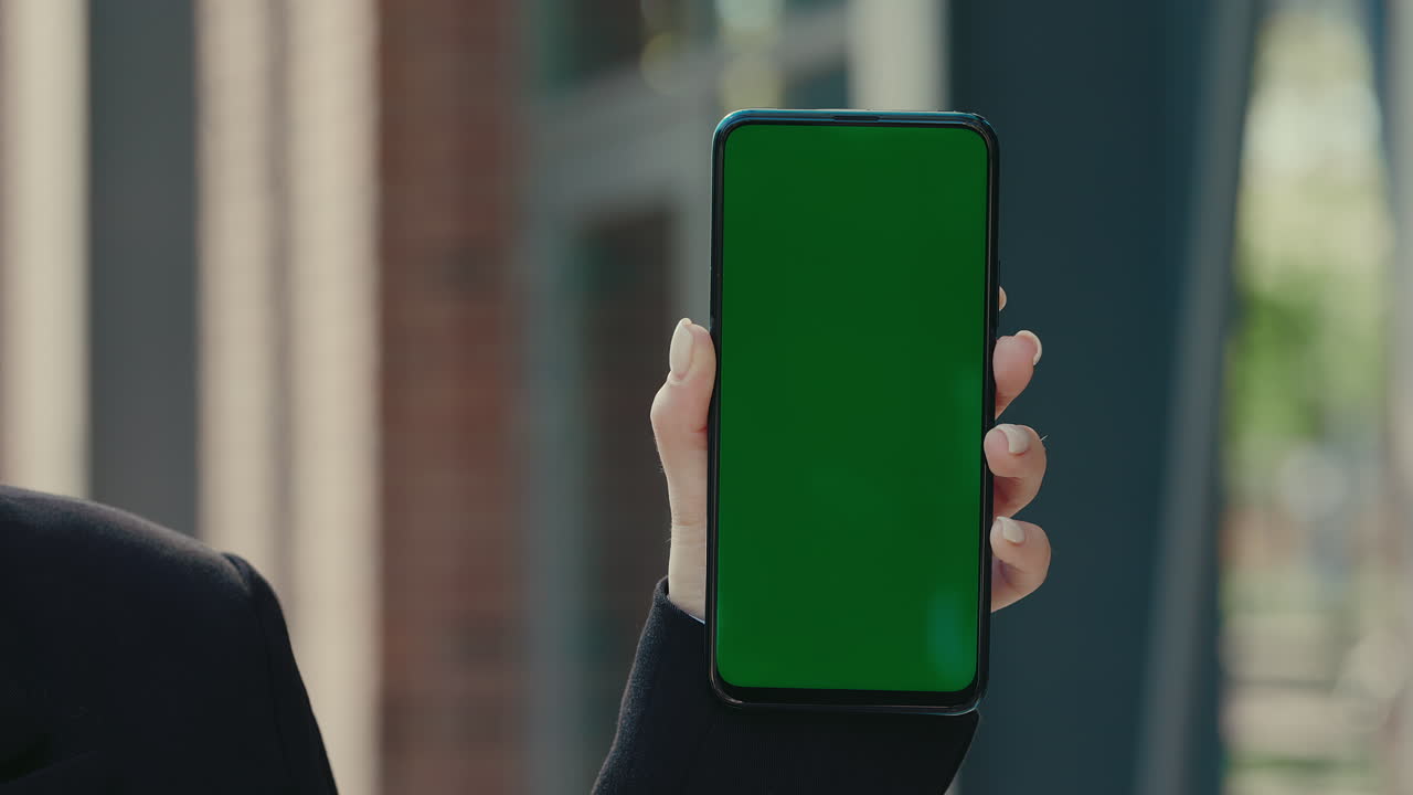 mujer sosteniendo un teléfono inteligente con una pantalla verde