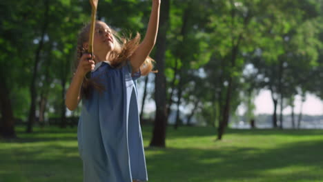 una chica alegre golpeando el lanzamiento de la lanzadera con una raqueta en el parque golden sunlight.