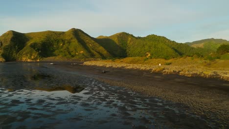 4x4-car-drives-on-black-sand-beach-during-low-tide-at-sunset,-Kiritehere