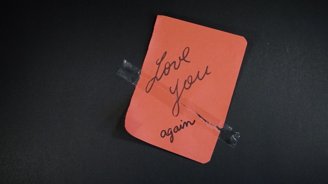 Broken red page with "Love you" message being put back together. Shot from above with the sony a7iii.