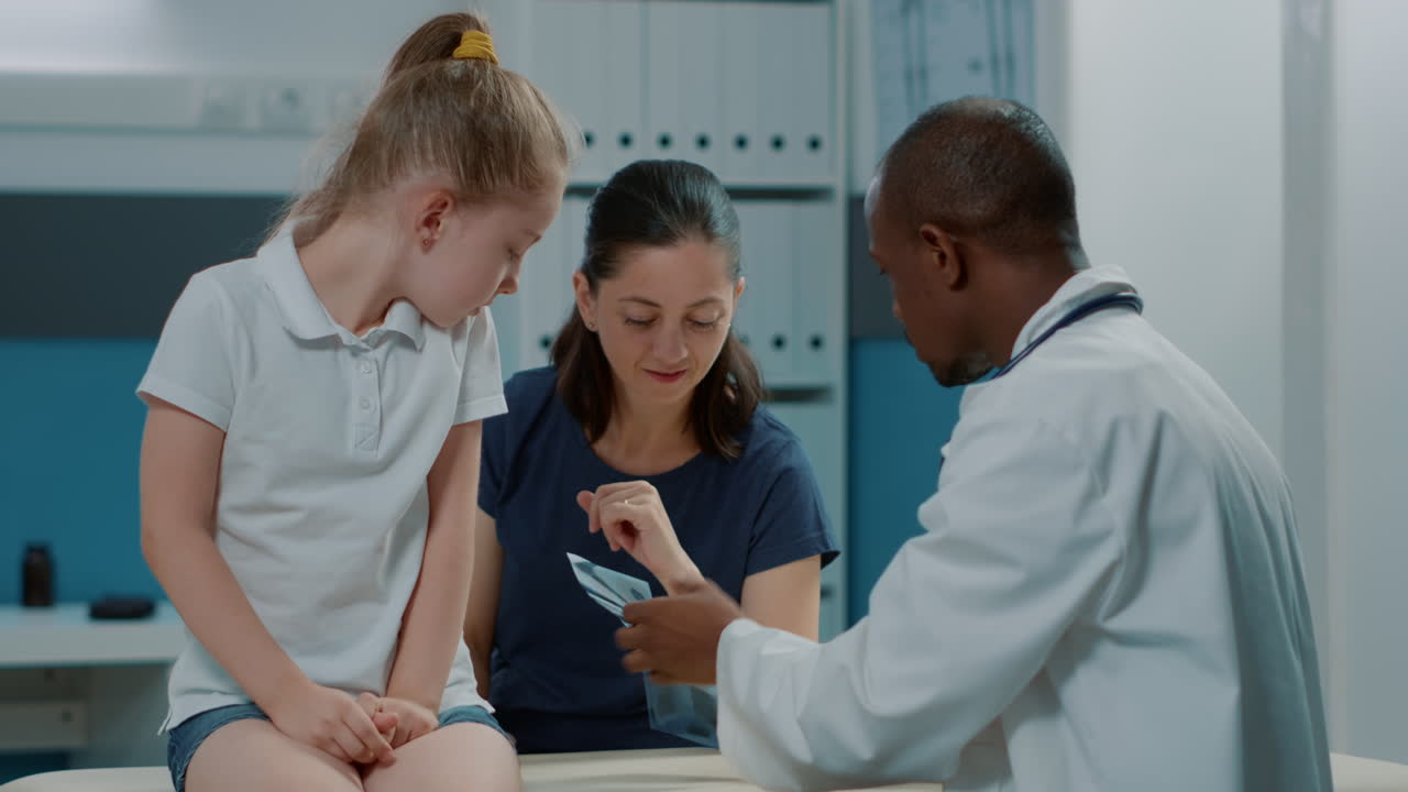 Doctor examining a child's X-ray with their mother in a clinic