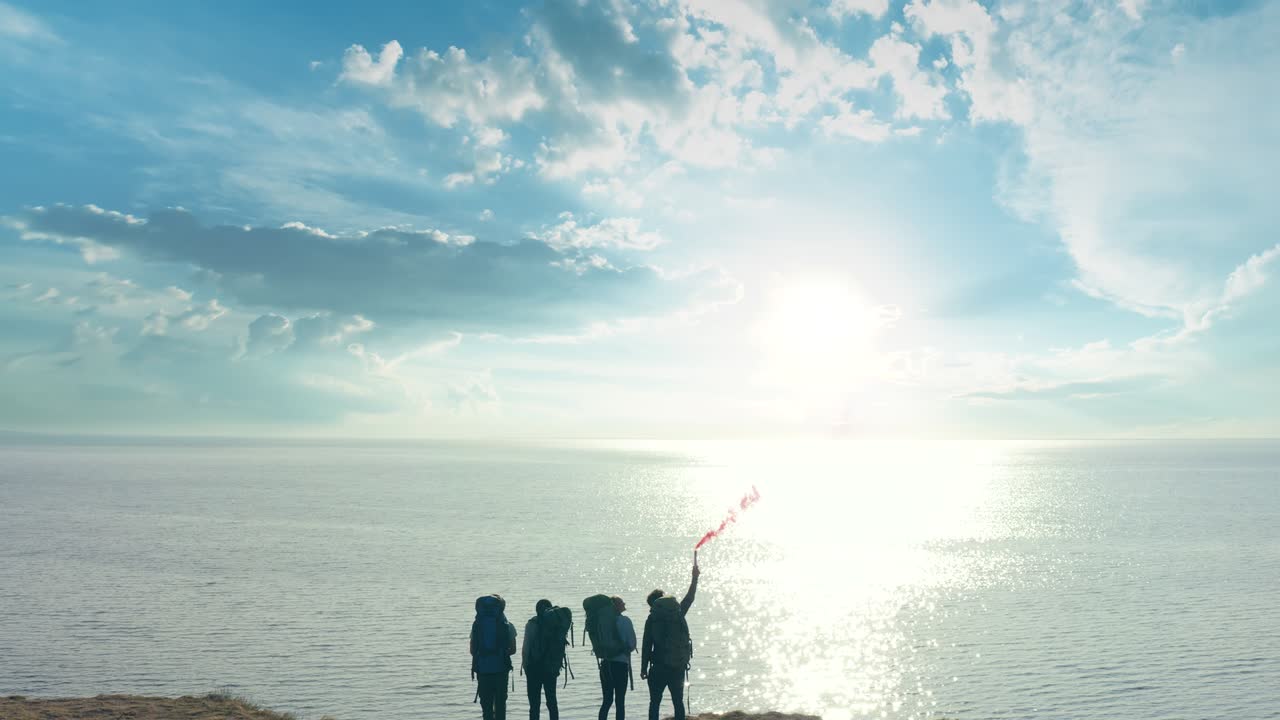 바다 근처의 모래 바위 꼭대기에 서 있는 불 지이를 가진 여행자 들