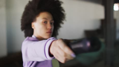 mixed race woman holding green flare standing in an empty building