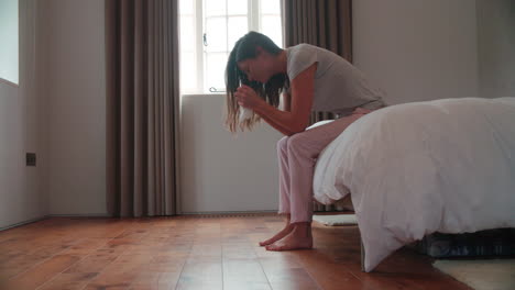 woman suffering from depression sitting on bed in pajamas