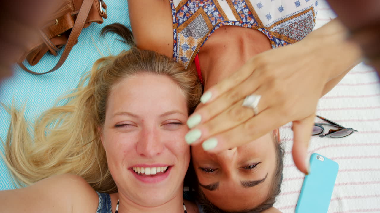 행복 한 친구 들 이 피크닉 담요 에 셀피 를 찍고 있다