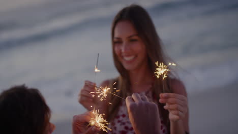 Glückliches-Junges-Kaukasisches-Paar,-Das-Silvester-Feiert-Und-Wunderkerzen-Am-Strand-Bei-Sonnenuntergang-Schwenkt-Und-Gemeinsam-Eine-Romantische-Feier-Mit-Echten-Menschen-Genießt