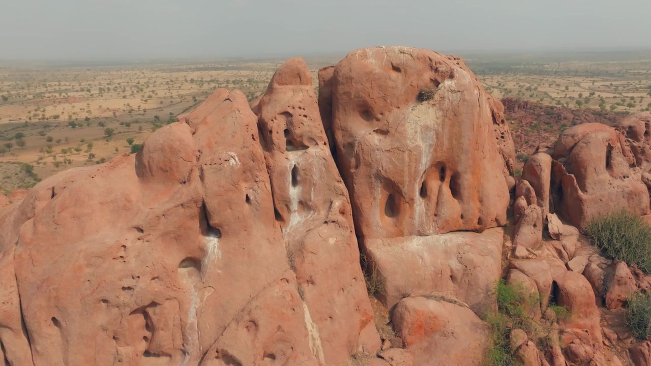 Sorvolo con drone di un imponente affioramento granitico modellato dagli agenti atmosferici nel Deserto di Thar, Sindh, Pakistan, che rivela pinnacoli arrotondati, profonde cavità e rada vegetazione lungo la cresta rocciosa