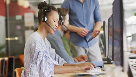 happy diverse business people sitting at table and using phone headsets at office