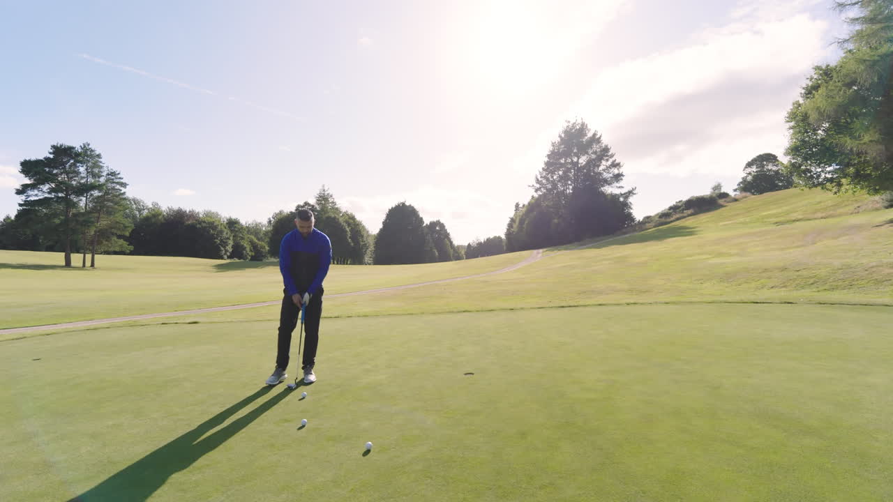Male golf player playing golf, hitting the ball with club on a golf course, copy space