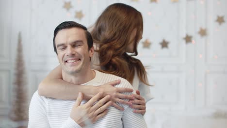 esposa sonriente pidiendo a su marido que cierre los ojos. familia alegre celebrando el año nuevo